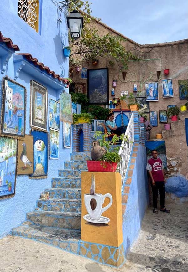 A stone staircase painted blue and highly decorated with people standing and sitting nearby